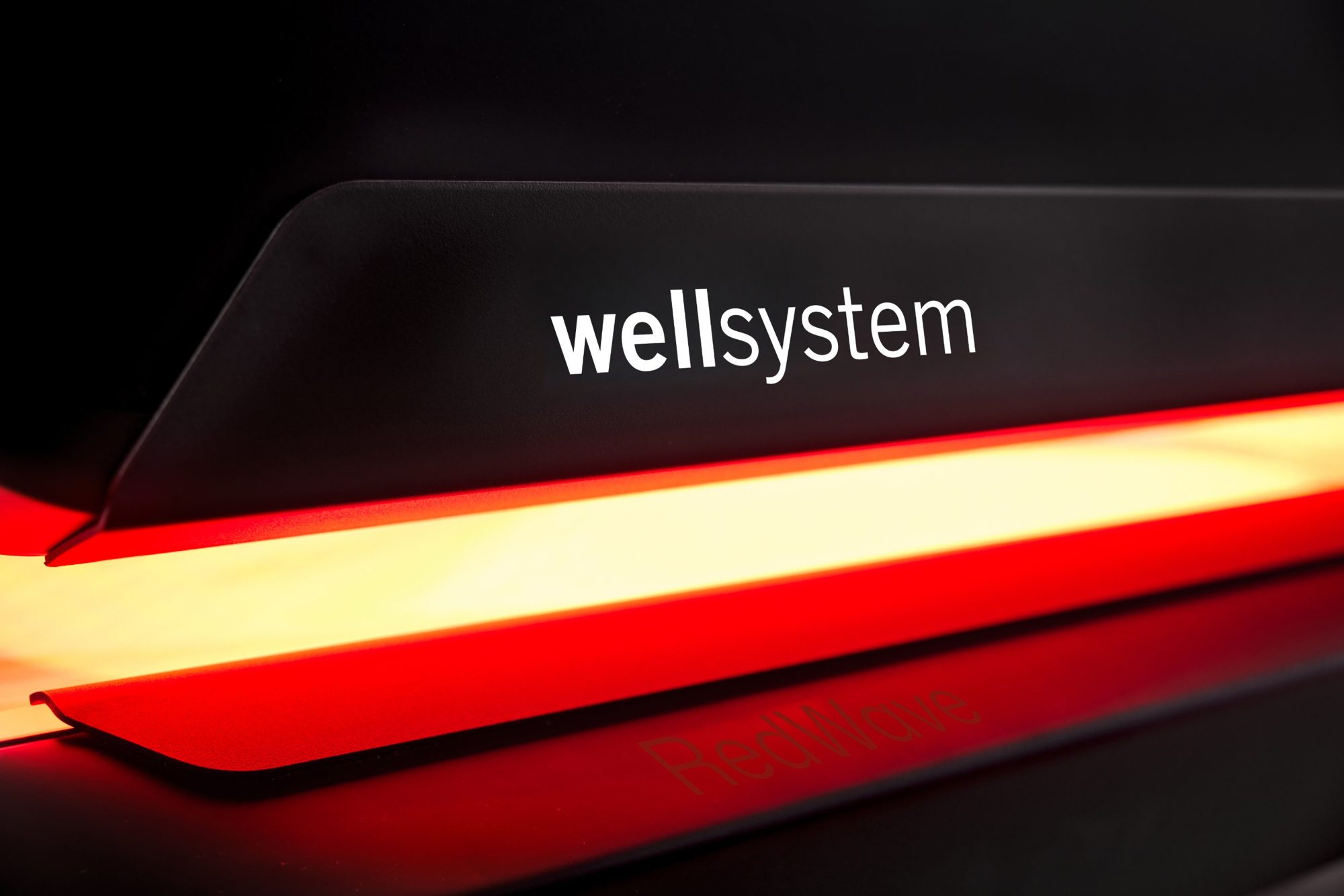 Close-up of the wellsystem logo above the glowing RedWave light strip