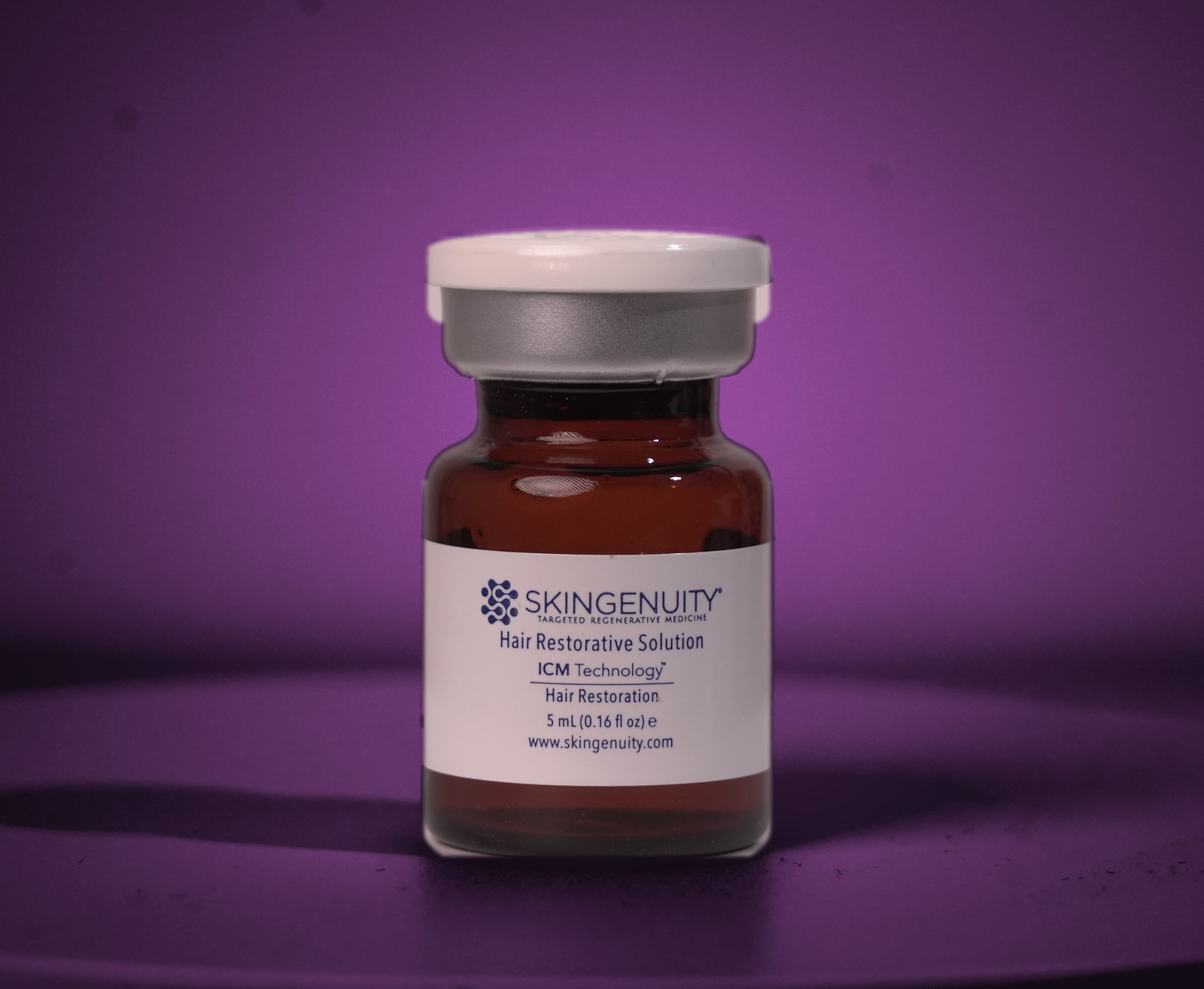 Skingenuity Hair Restorative Solution vial, lit on a plum studio backdrop
